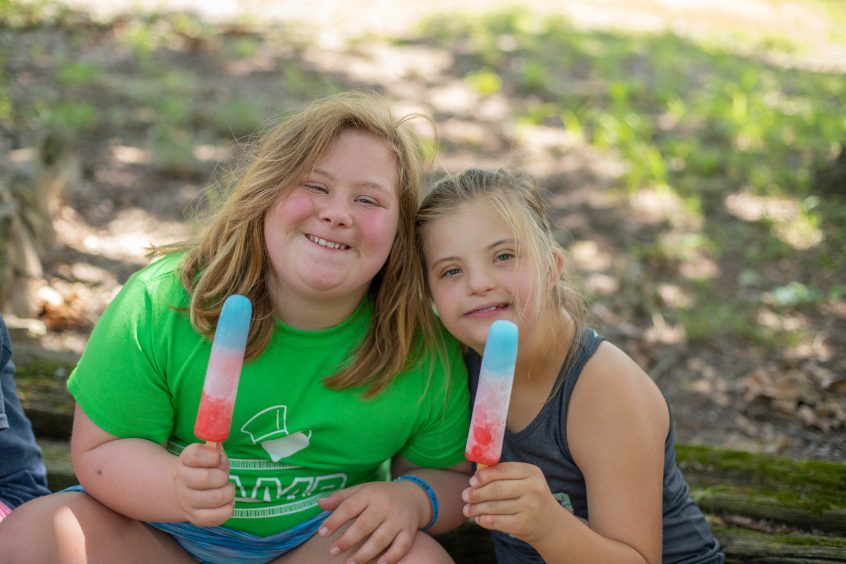 Two girls holding multicolored popsicles