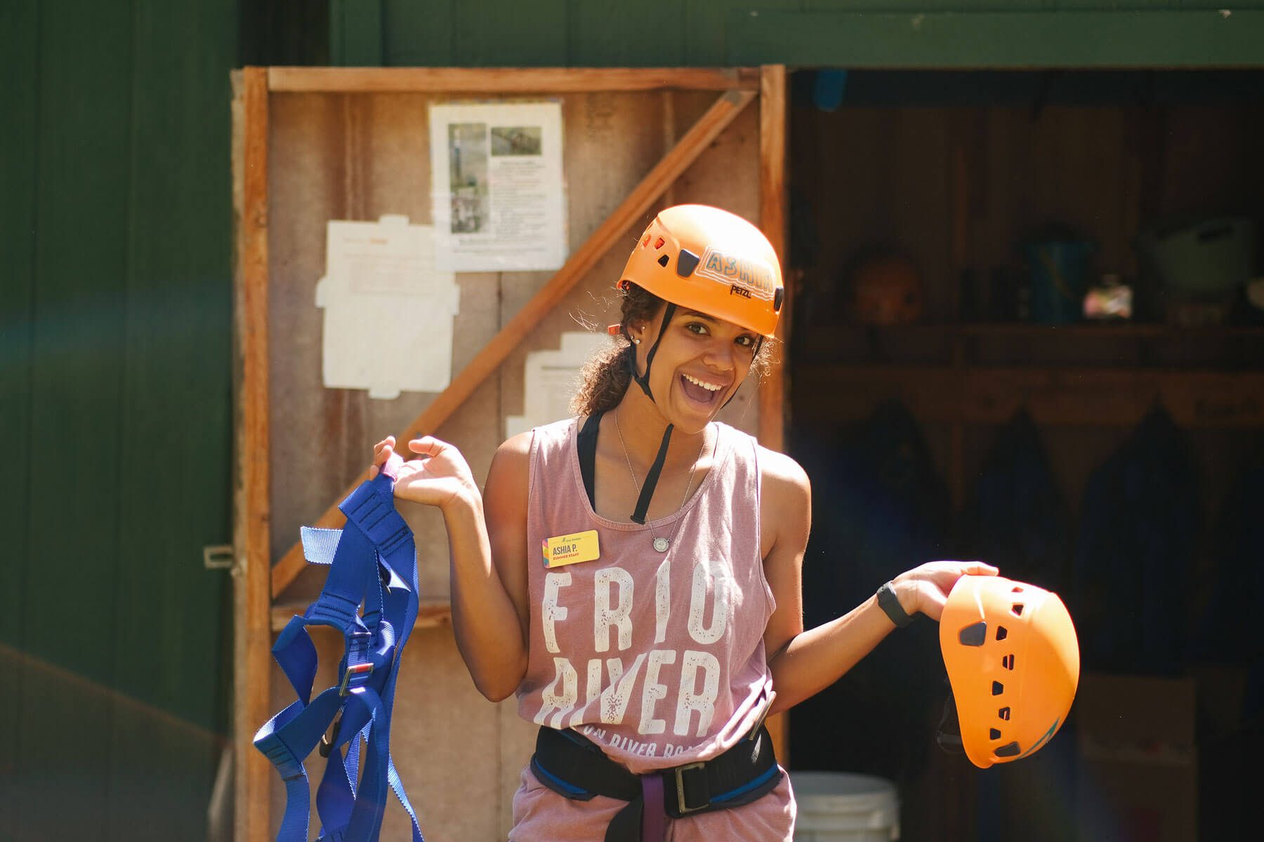 Summer camp counselor holding a helmet with a zipline harness