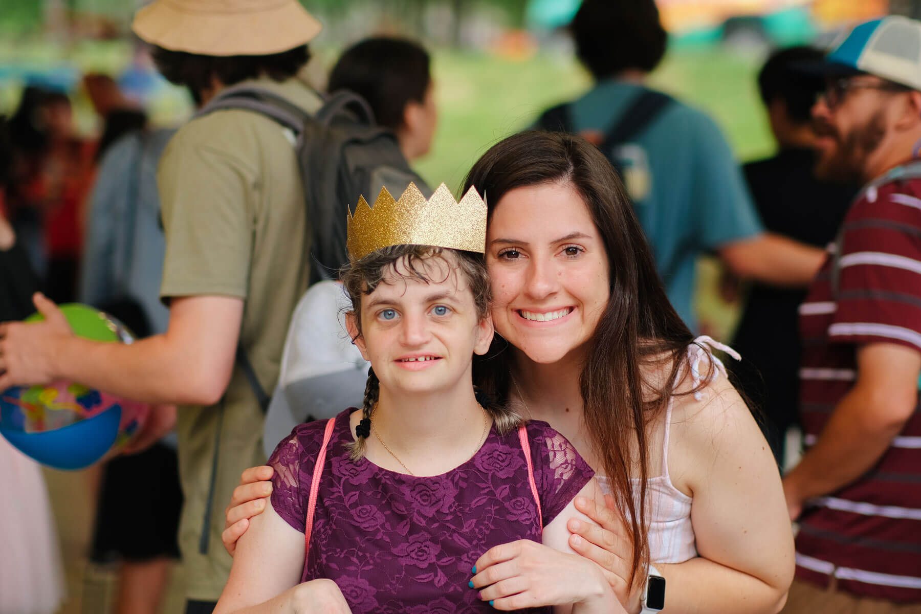 Summer camp counselor smiling with a camper wearing a paper gold crown