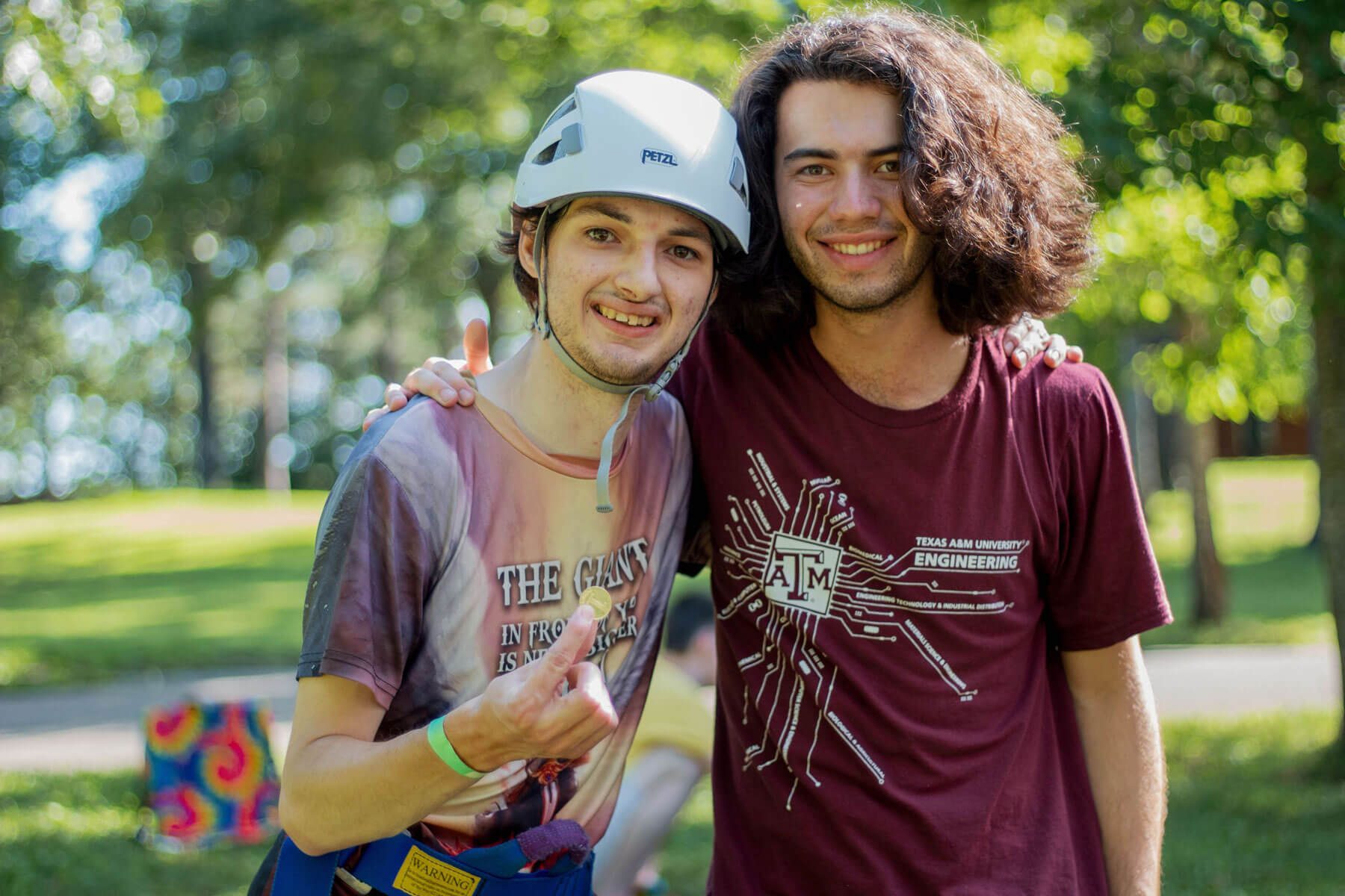Camper wearing helmet with a long-haired camp counselor smiling for the camera
