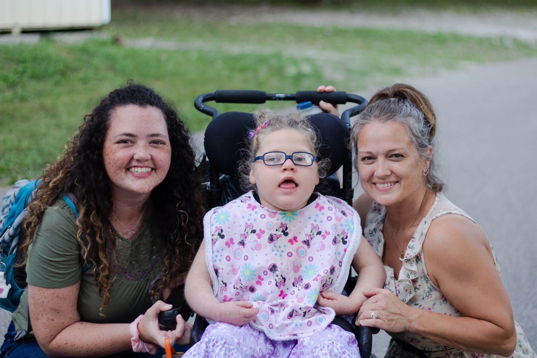 Nurses with a young girl in a wheelchair at camp barnabas