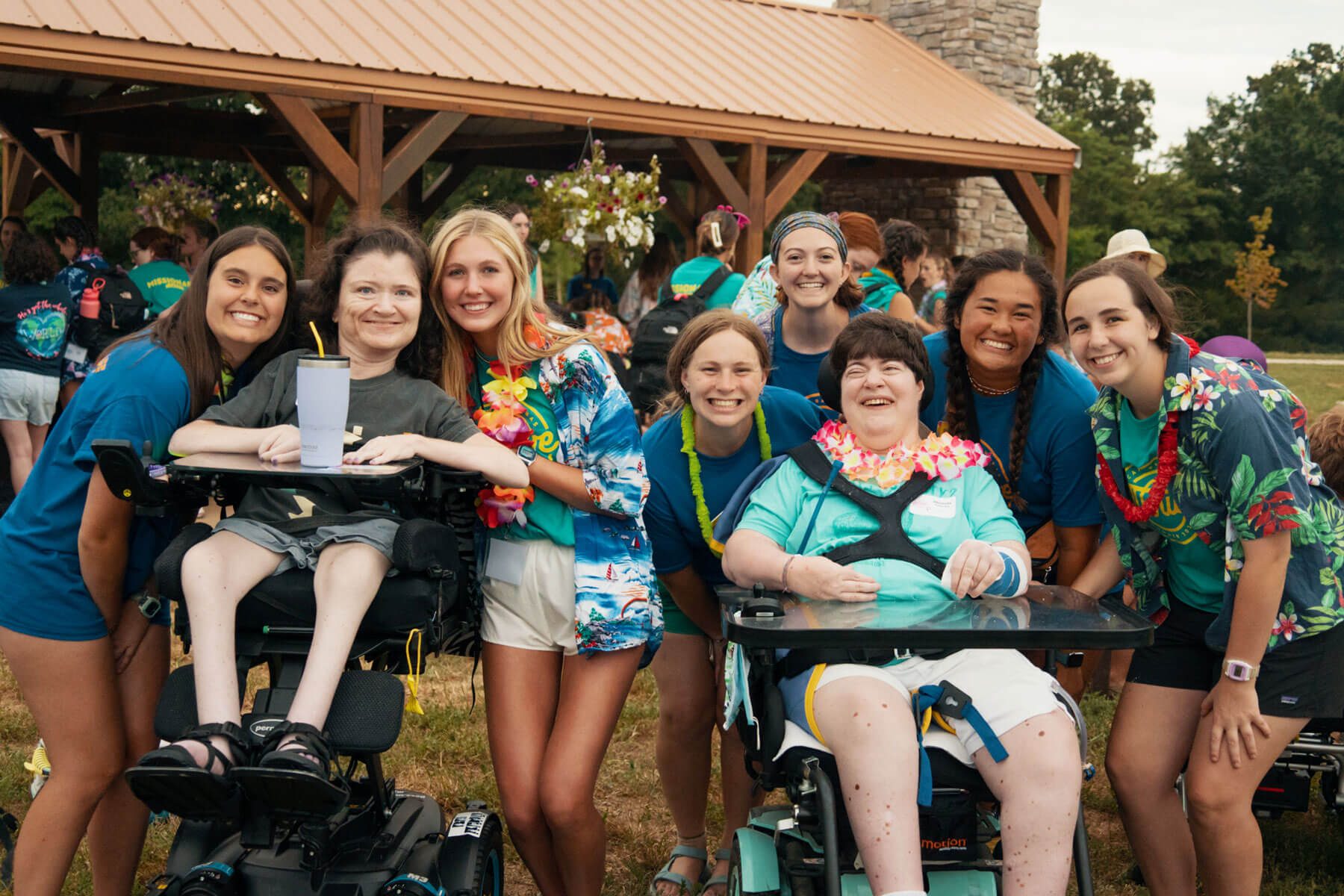 Summer camp counselors with campers in wheelchairs smiling