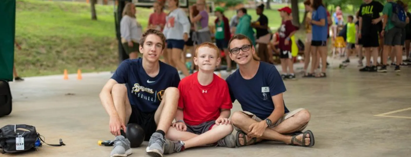 Campers sitting down on a concrete pad at summer camp
