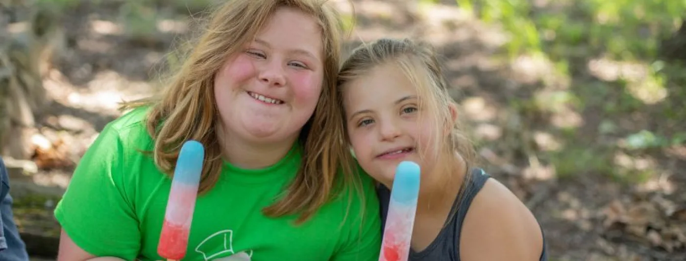 Two girls holding multicolored popsicles