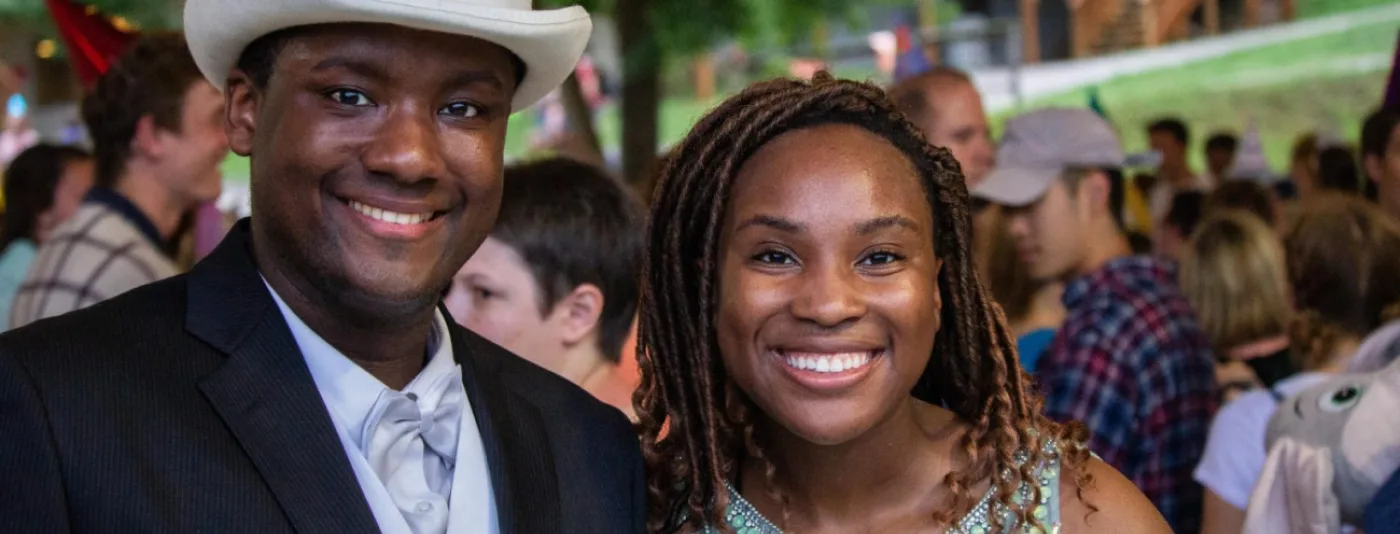 Two smiling people attending an outdoor camp event