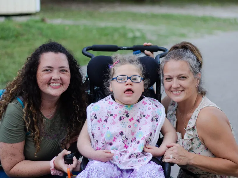 Nurses with a young girl in a wheelchair at camp barnabas