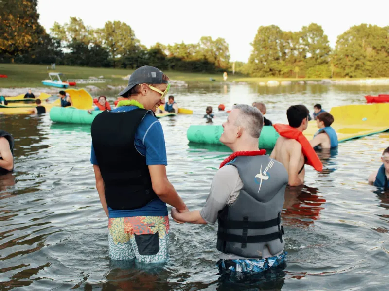 Campers and camp counselors wading in lake water
